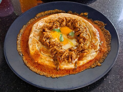Roti canai sarang burung traditional Malaysian flatbread with egg and shredded beef curry sauce