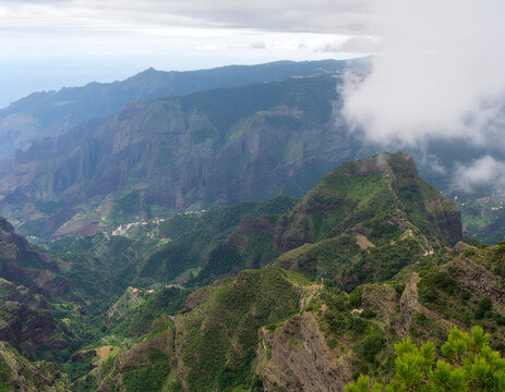 A breathtaking aerial view showcases a lush, mountainous landscape shrouded in mist, highlighting the dramatic topography and vibrant greenery of a remote island region.