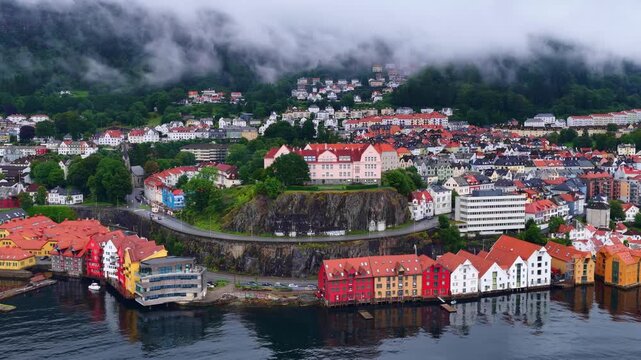 Orbiting drone shot of Bergen on a foggy morning, colorful houses at the waterfront in Bergen harbor, flying above Bergen old town in Norway, Scandinavian travel
