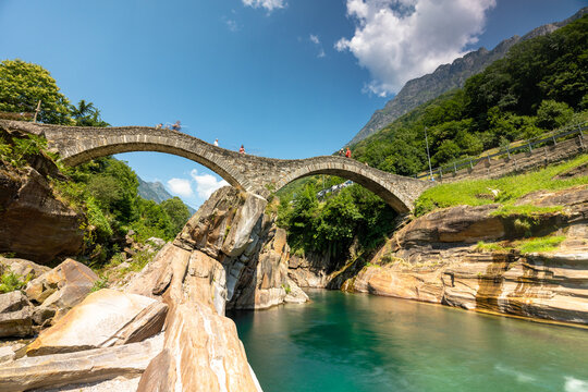 Historic Ponte dei Salti stone arch bridge over turquoise Verzasca river with rocky valley landscape in Lavertezzo, Switzerland