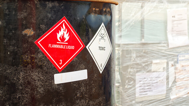 Toxic chemical with skull icon and flammable liquid warning sign on hazard chemical metal barrel. Industrial safety sign, close-up with selective focus