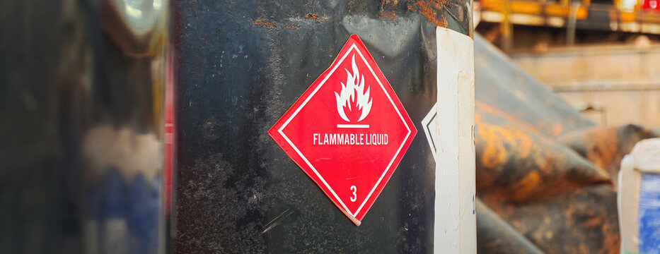Flammable liquid warning sign on the chemical metal barrel. Industrial safety sign on the object, close-up with selective focus.