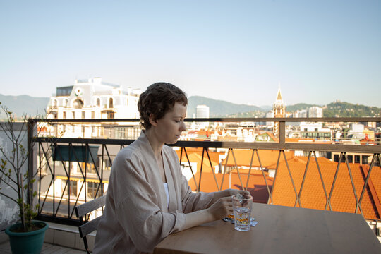 cancer patient prepares a daily dose from blister packs beside a glass of water on a sunny terrace, portraying home treatment, medication routine and independent recovery care