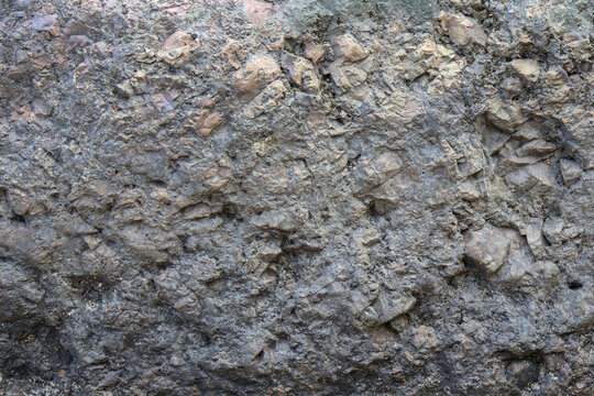 Close-up of coarse gray rock reveals intricate natural patterns and uneven surface.