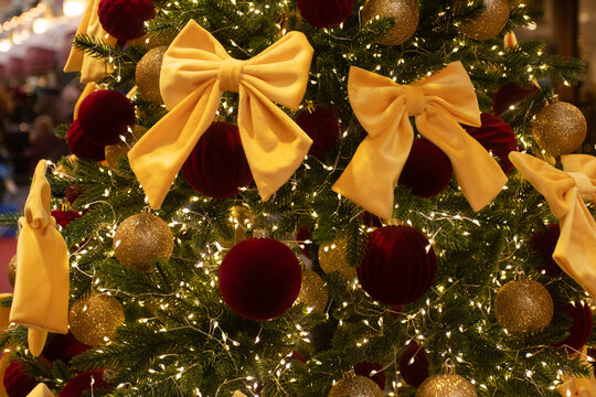 elegant christmas tree decorated with large golden bows,red velvet baubles and glitter ornaments, warm fairy lights and festive background bokeh, luxury holiday decor concept
