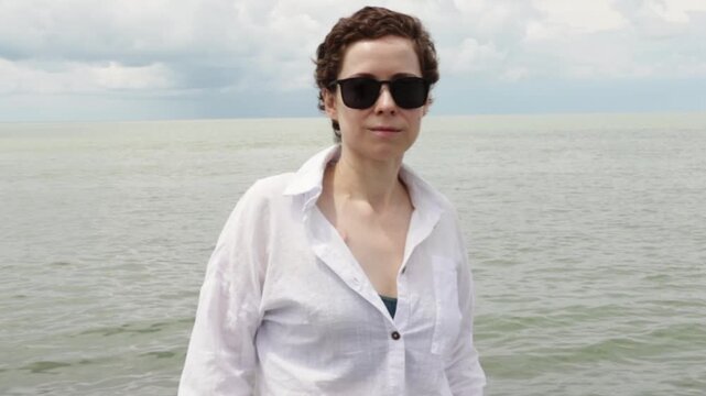cancer survivor in sunglasses relaxes by the sea during a restorative summer holiday, embracing sun safety, emotional recovery and wellbeing after breast cancer treatment