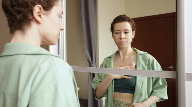 thoughtful woman looks down at her visible chemotherapy port in the mirror, showing quiet self monitoring, oncology self care and everyday life after breast cancer treatment