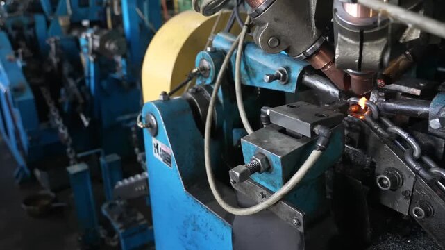 Heavy machinery welds and cools metal chains during automated industrial production inside a factory facility
