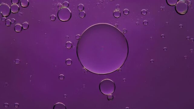 Close-up of oil droplets suspended in purple liquid background