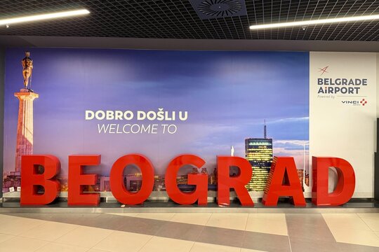 Belgrade, Serbia - June 22, 2026: Large red 3D lettering spelling BEOGRAD below bilingual welcome sign and landmark Pobednik wall mural at Belgrade Nikola Tesla Airport arrivals terminal interior