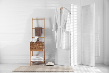 Naklejka premium Clean cotton bathrobe and towels with orchid flower in room