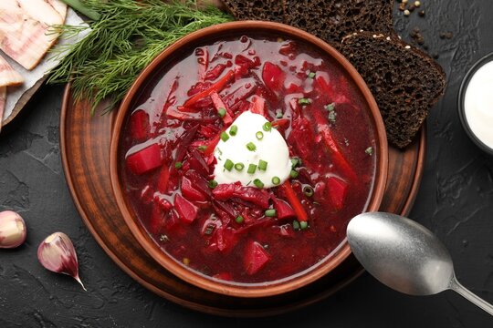 Delicious borscht served on black table, flat lay