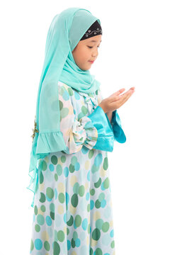 Side view portrait of cute young Asian Muslim girl praying with open hands isolated on white background.