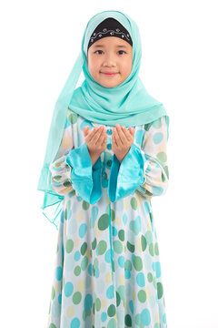 Half length portrait of cute young Asian Muslim girl praying with open hands isolated on white background.
