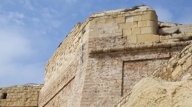 rounded bastion corner turret base rises from valletta fortification walls limestone masonry detail close limestone bastion wall knights of malta walls 16th century fortress fortified old town