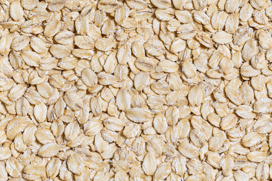 Raw organic rolled oatmeal flakes pattern background texture close-up