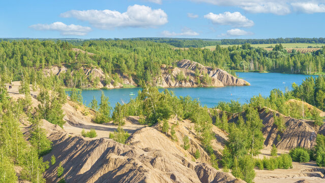 Breathtaking panoramic view of a massive canyon with unique clay hills and turquoise water under a blue sky with fluffy clouds in a natural setting  in Konduki, Tula region, Russia