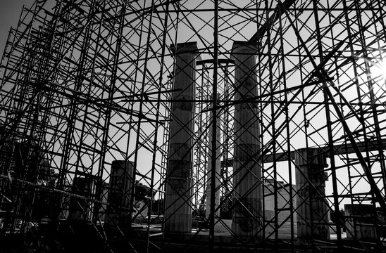 Epidaurus, Greece. The Sanctuary of Asclepius (Asclepieion) with scaffolding for site maintenance. Backlit image at sunset, black and white photo.
