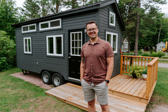 A man stands outside a small home on wheels