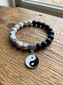 Stylish beaded bracelet showcasing a yin yang charm resting on a rustic wooden background