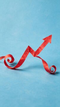 Red paper streamer shaped like a rising arrow graph on a blue background, symbolizing growth and birthday milestones for marketing campaigns