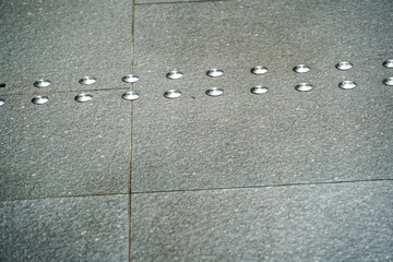 Fototapeta premium Tactile paving dots guide visually impaired pedestrians on a textured stone pathway