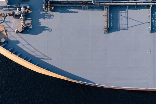 Overhead view of an industrial ship deck with teal plating and intricate pipe manifolds for maritime transport and fuel logistics