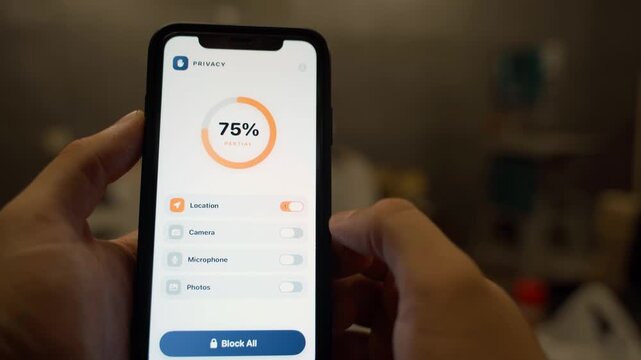 Hands holding smartphone with privacy settings app showing app permissions toggles