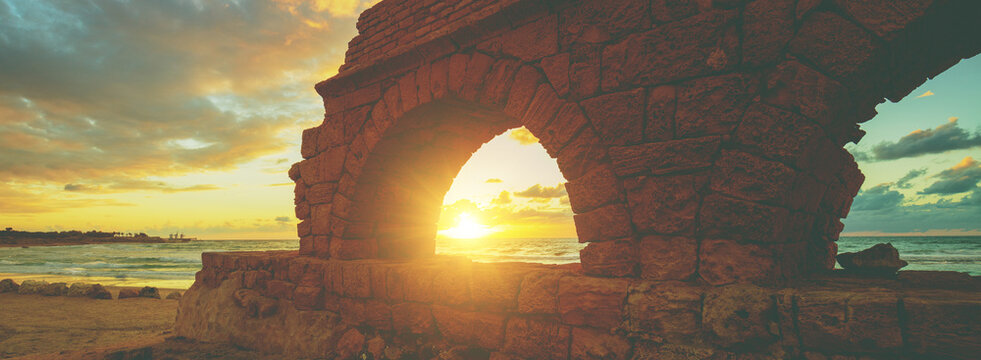 Remains of the ancient Roman aqueduct in ancient city Caesarea at sunset. Israel.