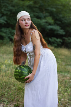 Cottagecore style female model holding big watermelon in forest