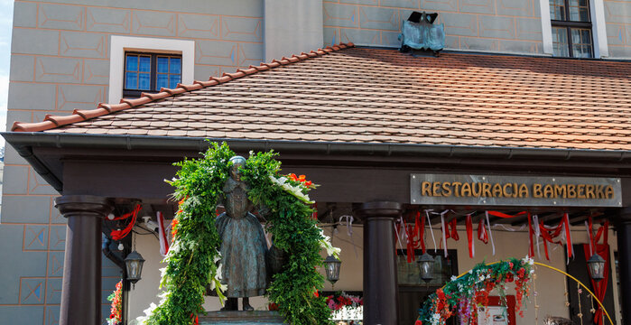 Poznan, Poland &mdash; August 2026: Bamber Day. The Bamberka Well monument adorned with a decorative green garland during the annual Święto Bambr&oacute;w festival at the Old Market Square.