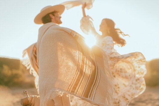 Young couple in traditional Chilean huaso attire dancing the cueca outdoors, featuring a woven wool poncho and flowing floral skirt for national heritage and cultural celebration