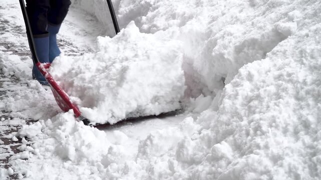 Close-up action of a person clearing heavy fresh snow with a shovel during winter snowfall in Morioka, Japan.