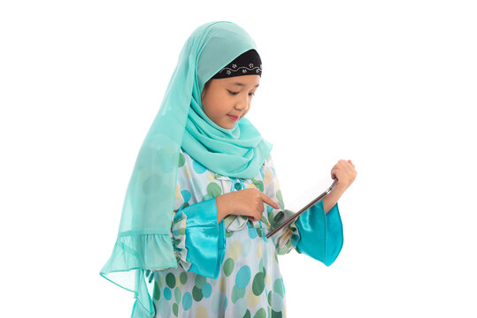 Charming young Asian Muslim child using touchpad computer for online learning e-learning concept.