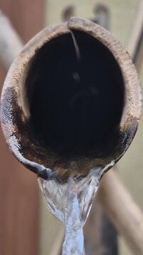 Extreme close up of water dripping from a pipe conceptualizing drought and water scarcity