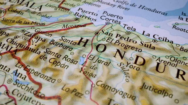 Gliding macro view over physical atlas map from Honduras to Guatemala