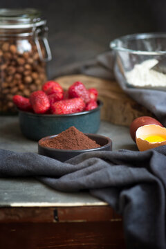 Close-up of assorted Ingredients for making a chocolate strawberry cake including strawberries, cocoa powder, eggs, and flour