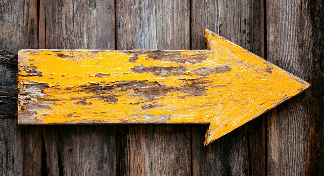 Rusty arrow sign pointing right with yellow weathered paint