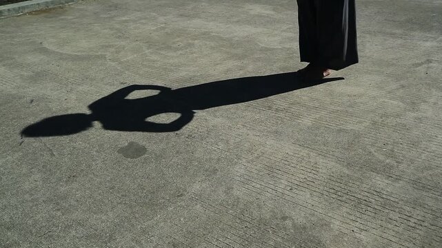 A long shadow of a person standing on a concrete ground surface. daily outdoor welness activity