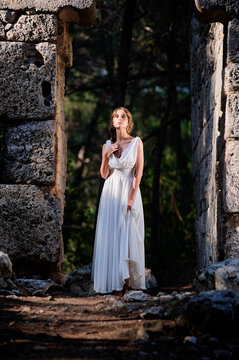 Young beautiful woman wering white dress at antique ruin
