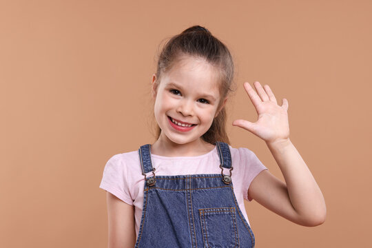 Portrait of happy little girl on brown background