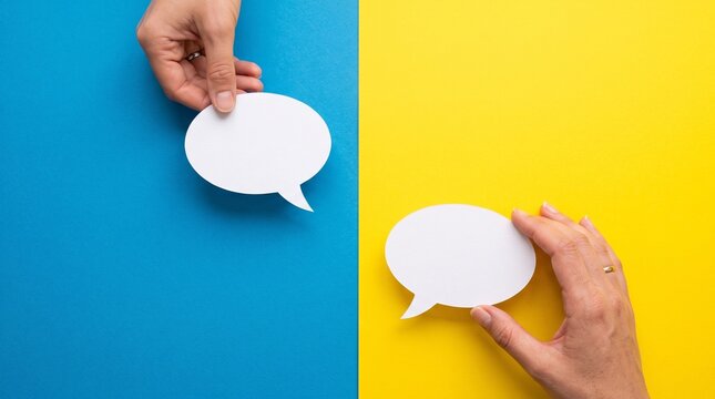 Female hands holding white speech bubble cutouts against vibrant blue and yellow background representing communication and dialogue for social media