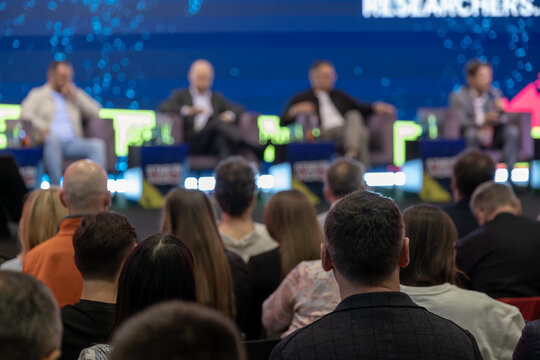 Conference audience watches four seated speakers take part in a panel discussion on stage.