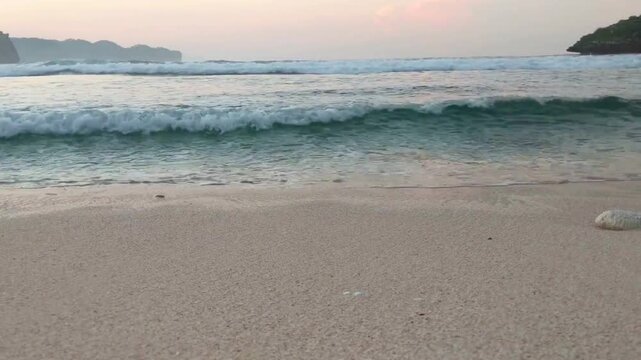 Gentle ocean waves rolling onto a sandy beach at sunset