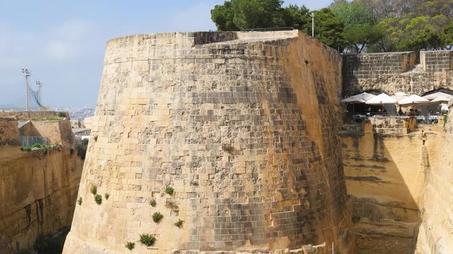 trees crown a valletta bastion corner overlooking cafe terraces historic fortification rampart wide view star fort corner sentry turret vedette watchtower fortification corner limestone bastion wall