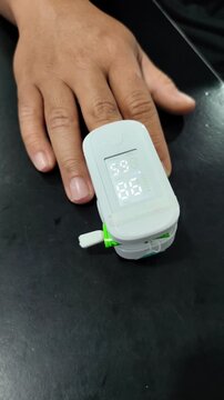 Doctor measuring blood oxygen saturation with pulse oximeter. Close-up of a medical professional attaching a fingertip pulse oximeter to a patient's hand to monitor vital signs, checking oxygen level