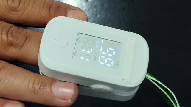 Doctor measuring blood oxygen saturation with pulse oximeter. Close-up of a medical professional attaching a fingertip pulse oximeter to a patient's hand to monitor vital signs, checking oxygen level
