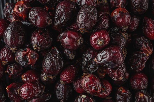 dried red rose hips on a black wooden rustic background