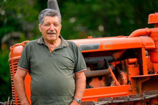 Anziano agricoltore sullo sfondo il vecchio trattore