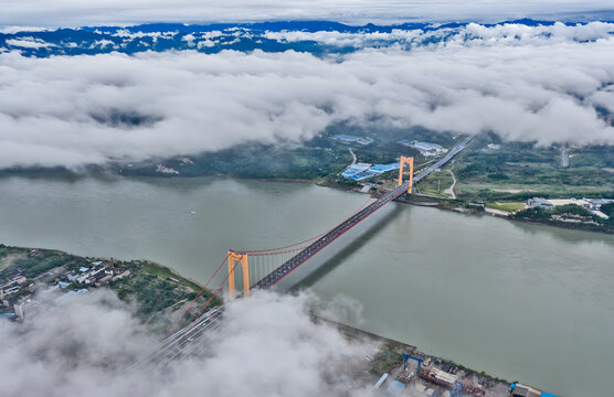 Red Suspension Bridge Over River in Cloudy Mountain Landscape